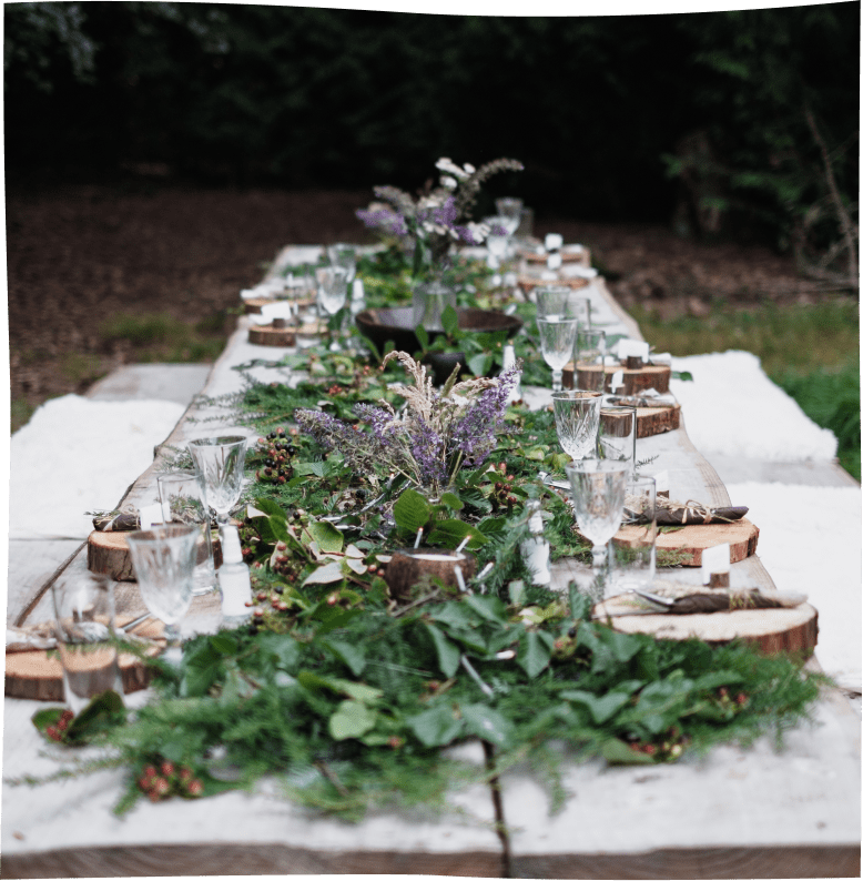 Nomadic's large communal wood table crafted from a fallen tree with an invernal green-leaf and bluebells decoration