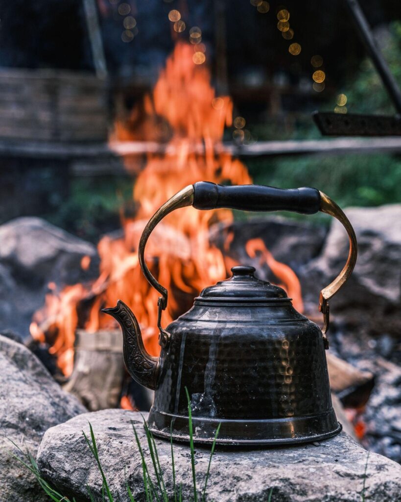A kettle over an open-grill fire