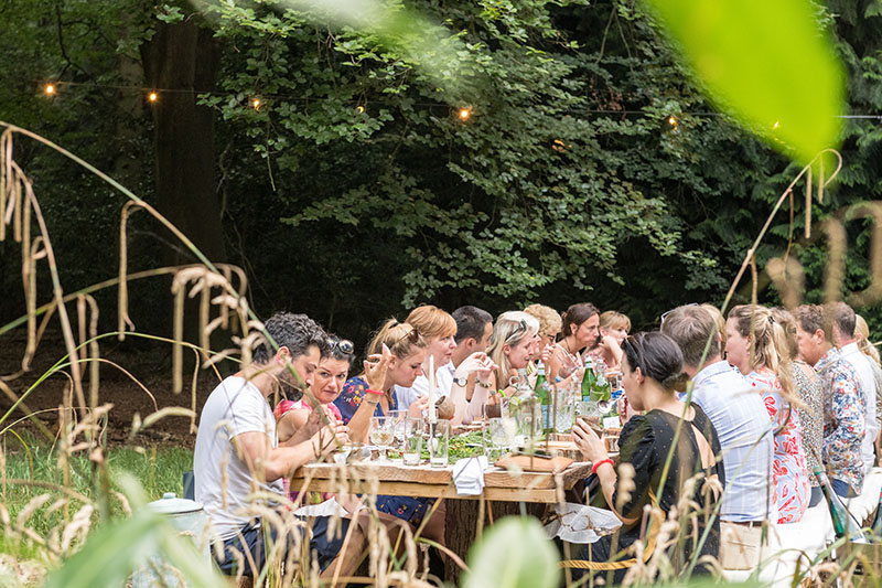 A big group of people seated at Nomadic's communal wood-crafted table