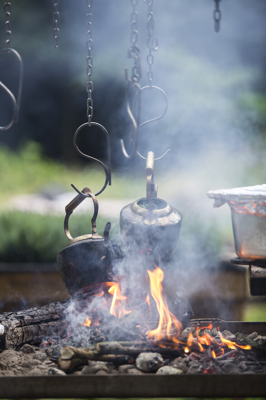 Two kettles hang in chains over an open fire