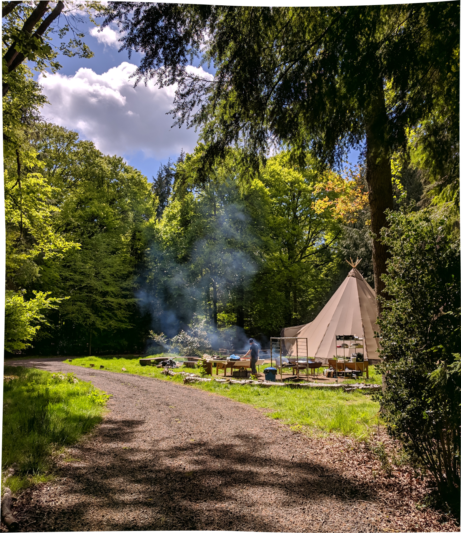 One of our tipis is spotted in the back of an open-fire cooking, in a beautiful cloudy day at Nomadic's woodland