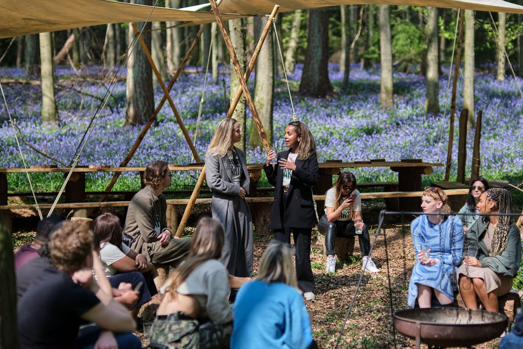 People seated and talking in a round surrounded by Nomadic's woodland for Meta's World Earth Day Corporate Experience